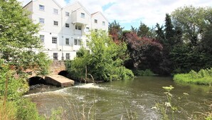 A riverside view with a white building with multiple windows and a bridge. - Cosy Cottage with log burner, in the hart of the Norfolk countryside (Buxton)