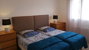 Ein Schlafzimmer mit einem Bett, zwei Nachttischen und einer Hängelampe.
