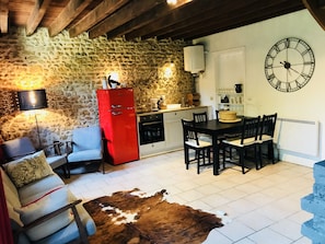 Cozy space with a stone wall backdrop, featuring a dining table, sofa, and cowhide rug.