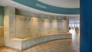 A reception area with a curved bench and a wall displaying "MAJESTIC BEACH TOWERS". - Incredible Gulf Front 1BD, Pools, Hot Tubs, and Free Attraction Tickets! (Panama City Beach)