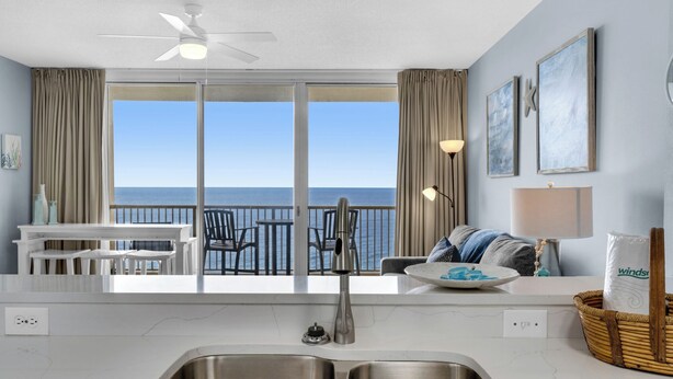 A modern kitchen with a large sliding glass door leading to a balcony with ocean views. - Incredible Gulf Front 1BD, Pools, Hot Tubs, and Free Attraction Tickets! (Panama City Beach)