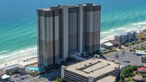Un hotel de gran altura con varias plantas, una piscina y vistas a la playa.