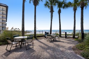 A patio area with outdoor seating and a view of the beach.