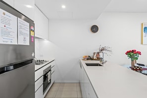 Eine moderne Küche mit einem Edelstahl-Kühlschrank, einem Gasherd und einem Spülbecken.