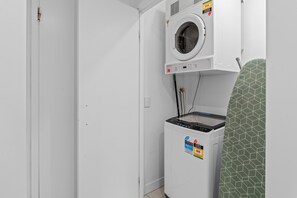 Un lavadero pequeño con lavadora y secadora, un panel de control y una toalla verde estampada.