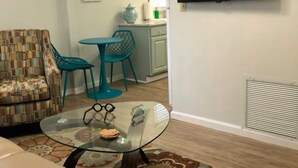 Een woonkamer met een bank, een glazen salontafel en een kamerbreed tapijt.