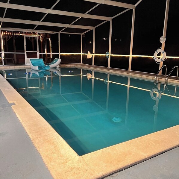 Una piscina interior con agua cristalina, un flotador salvavidas y una silla de descanso.