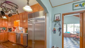 A kitchen with wooden cabinets, stainless steel appliances, and a hanging pot rack.