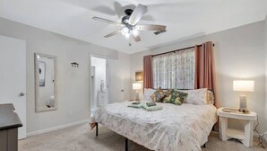 Un dormitorio con cama, mesitas de noche, ventilador de techo y espejo.