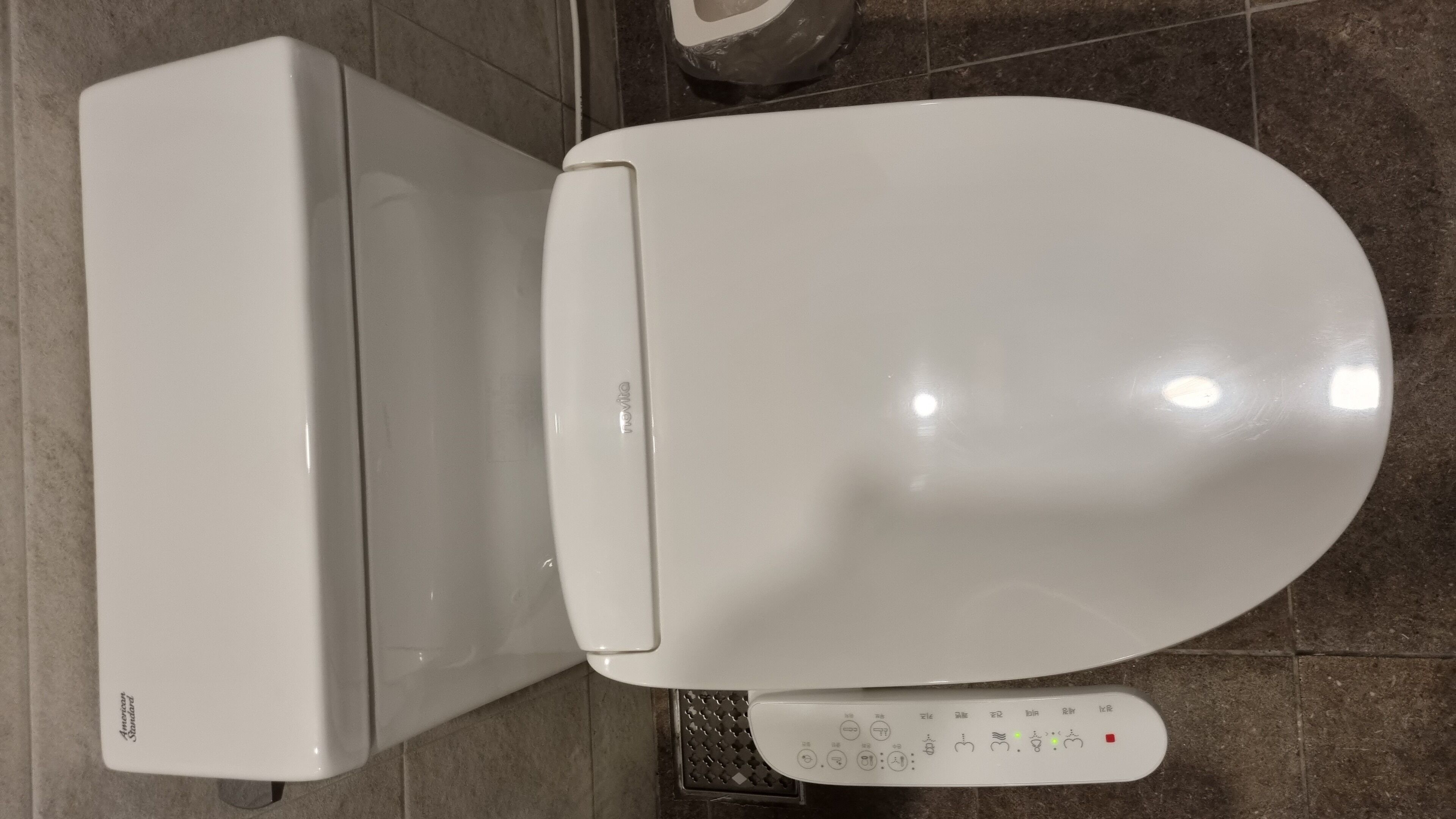A white toilet with a control panel featuring multiple buttons and a flush handle.