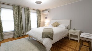 Une chambre à coucher bien rangée, avec un lit, une table de chevet, une lampe et une petite commode.