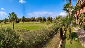 A well-maintained golf course with a clear sky, surrounded by lush greenery and palm trees. - Cozy and quiet apartment (Motril)