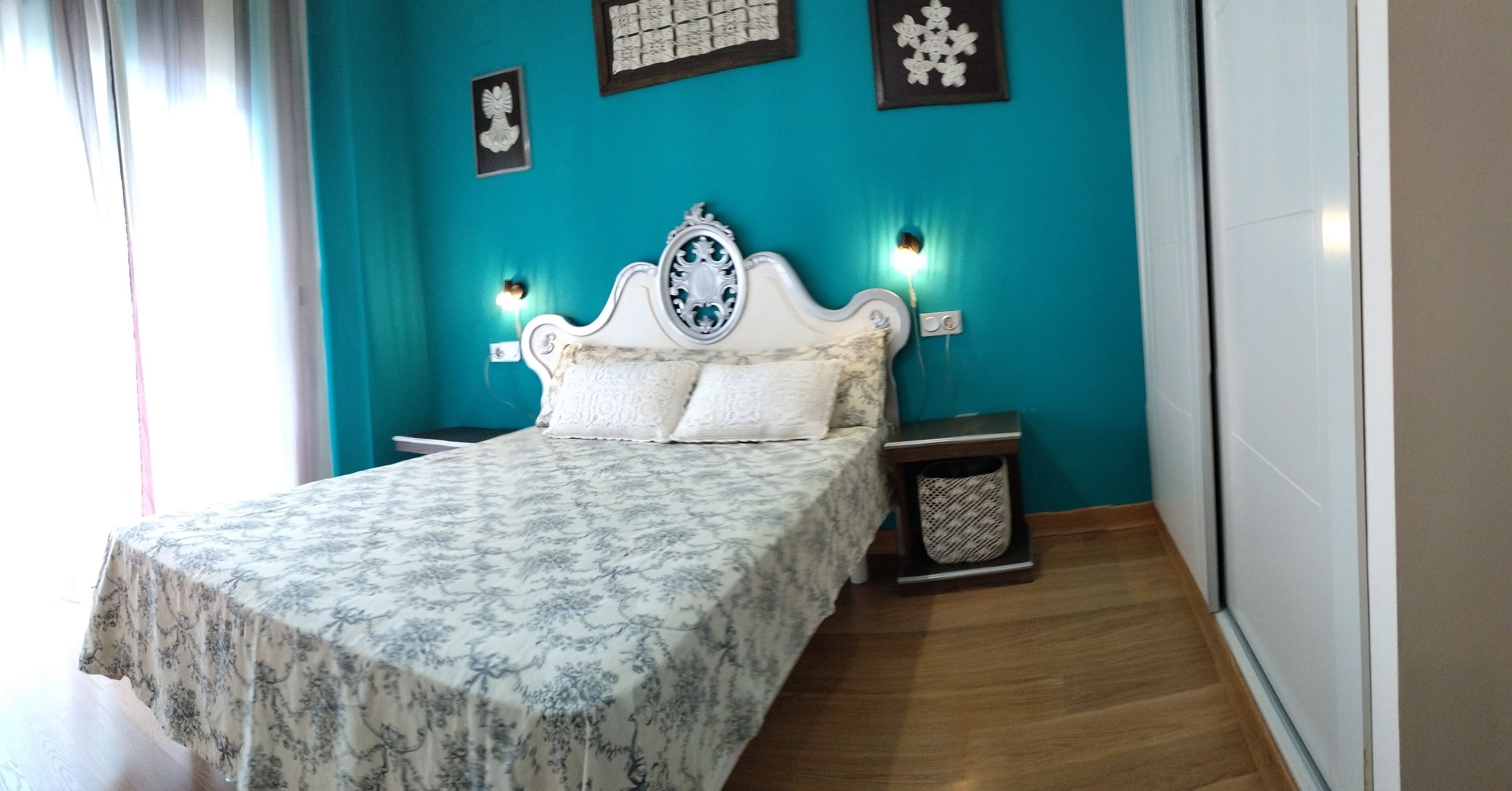 A bedroom with a bed, nightstands, and a wall-mounted lamp.