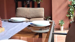 A dining table with plates and cutlery, a cushioned chair, and potted plants. - Cozy and quiet apartment (Motril)