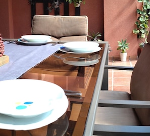 Enjoy al fresco dining in this serene outdoor space, complete with a glass table and comfortable seating for two.