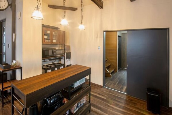 A modern kitchen with wooden cabinets, a central island, and pendant lighting. - Yadoya YADOKARI (Pippu)