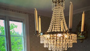 A dining room with a chandelier, a table set with food, and a window with a view of greenery. - Toftahult Gård (farm) (Ryd)