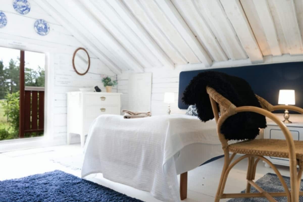 A bedroom with a bed, a chair, a dresser, and a mirror.