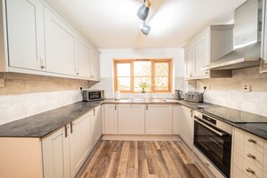 Une cuisine moderne avec des meubles blancs, un plancher en bois, une fenêtre offrant une belle vue et une hotte de cuisine Bosch.