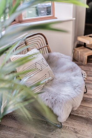 Una habitación con una silla de mimbre, un sofá blanco y mullido, y una mesa de madera.