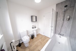 Un baño moderno con inodoro, lavamanos y bañera blancos.