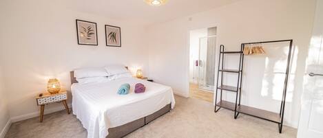 A bedroom with a bed, bedside lamps, a wardrobe, and a shower area.
