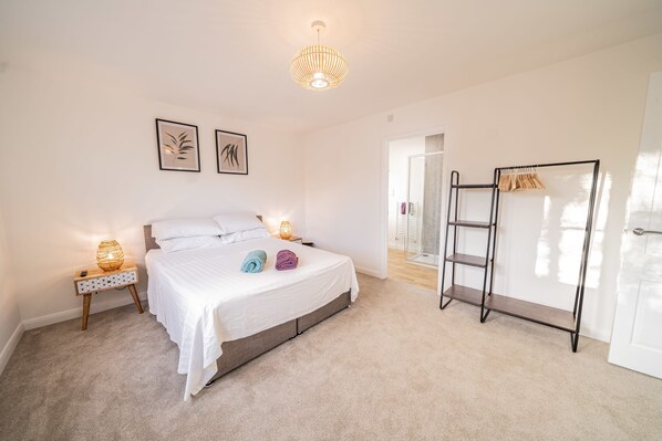 A bedroom with a bed, bedside lamps, a wardrobe, and a shower area.