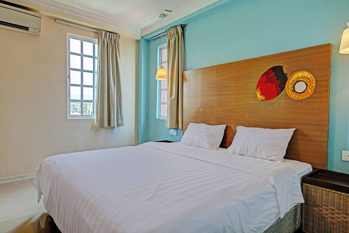A large bed with white linens, a wooden headboard, and a wall-mounted artwork.