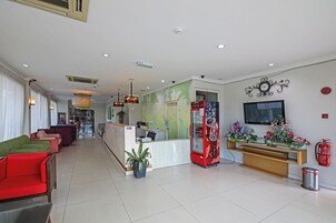 Un vestíbulo de hotel con mostrador de recepción, zona de estar y refrigerador.