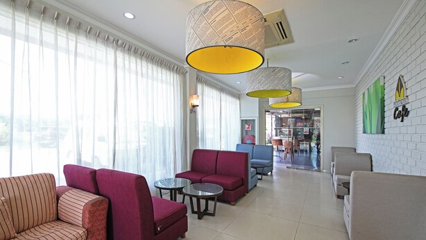 A hotel lobby with multiple seating areas, including sofas and armchairs, and a visible entrance to the restaurant. - Hotel O Northern Inn (Kota Marudu)