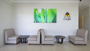 A modern interior with a white brick wall, a logo for 'Northern Cafe', and a seating arrangement of two sofas and two small tables. - Hotel O Northern Inn (Kota Marudu)