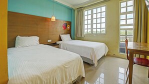 A hotel room with two beds, a wooden headboard, a table with a chair, and a window with curtains. - Hotel O Northern Inn (Kota Marudu)
