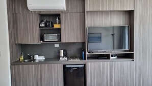 A modern kitchen with a built-in microwave, toaster, and coffee maker, a large flat-screen TV, and a compact dishwasher. - Bright and cozy studio in the heart of Recoleta (Buenos Aires)