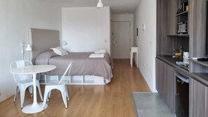 A modern, compact bedroom with a bed, bedside tables, a small white desk, and a chair. - Bright and cozy studio in the heart of Recoleta (Buenos Aires)