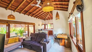 Amplia sala de estar con un sofá, una mesa de comedor y una cocina al fondo.
