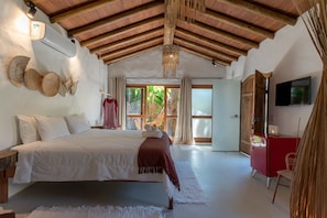 Quarto com cama, um armário vermelho, televisão e uma janela grande.
