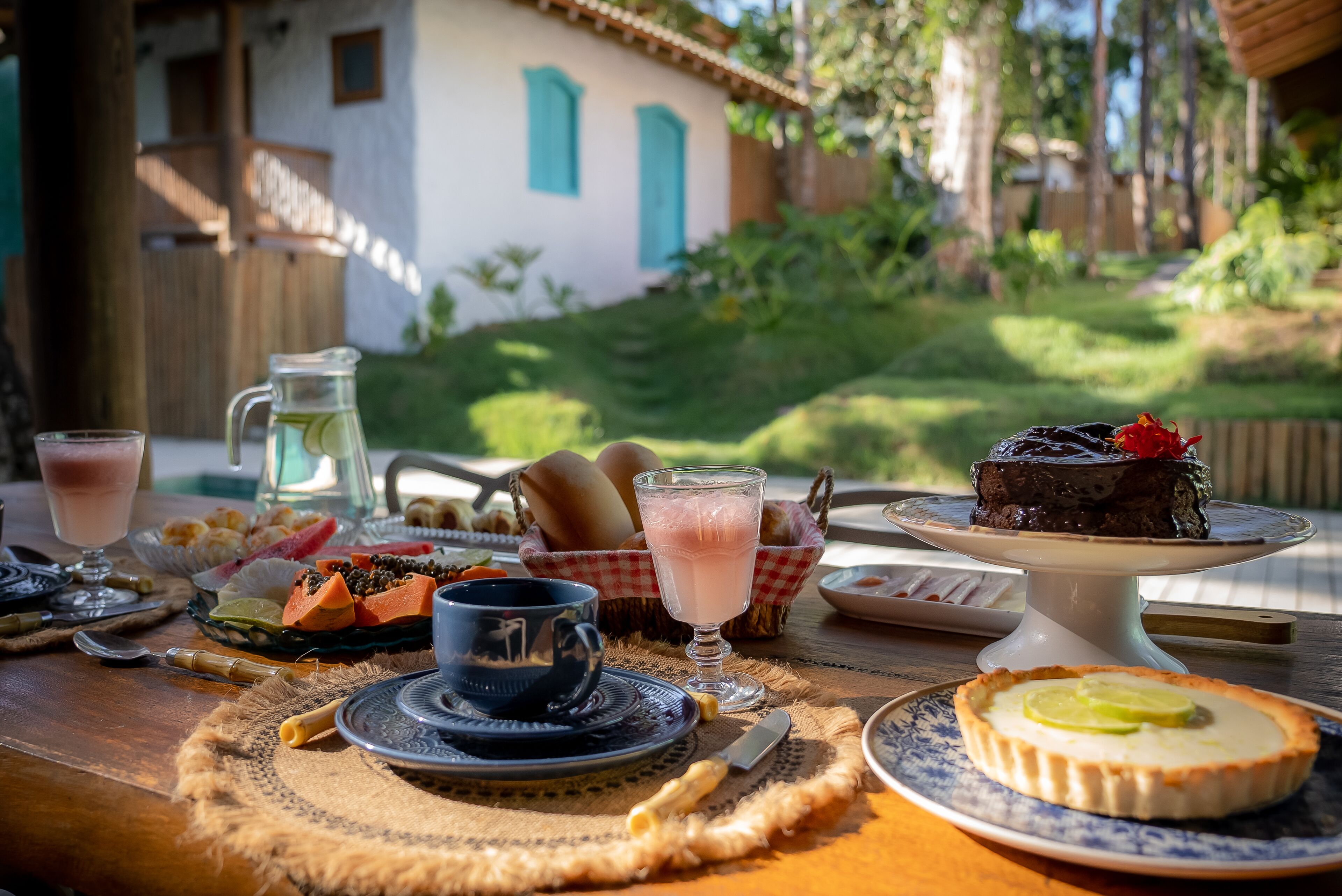 A table set with a pitcher, a glass of drink, a plate with food, and a dessert on a stand.