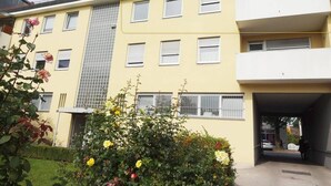 Um edifício de vários andares com fachada amarela, várias janelas e entrada coberta.