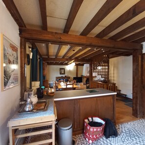 A cozy kitchen with wooden beams, a dining area, and a bar area. - Family chalet in a quiet location with a view of the Mont Blanc massif (Les Houches)