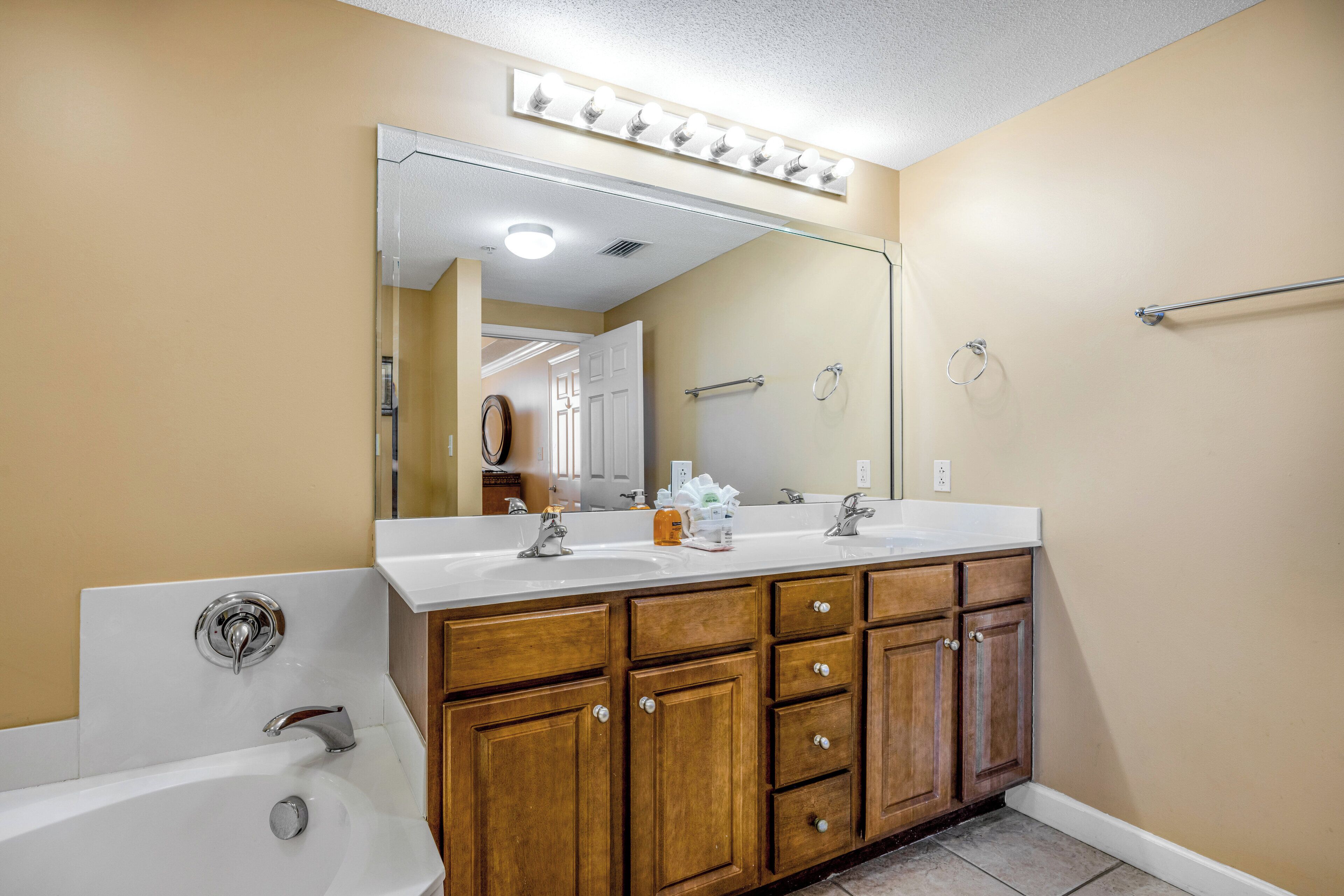 Une salle de bain avec un meuble-lavabo à deux vasques, un grand miroir et une baignoire.