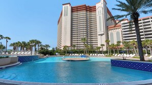 Ein Hotel mit einem großen Pool, Palmen und einem Hochhaus mit Balkonen.