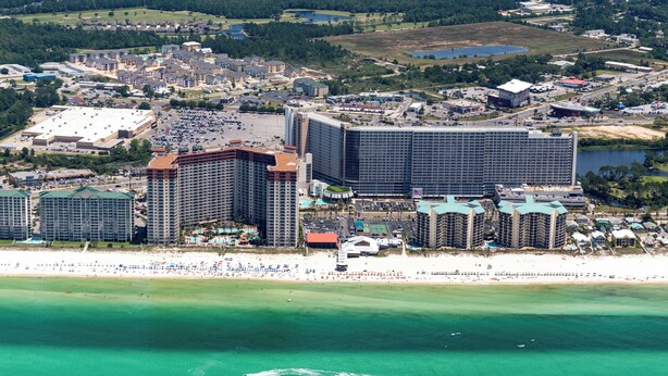 Eine Luftaufnahme einer Küstenstadt mit einem großen Hotelkomplex, einem Strand und umliegenden Gebäuden.