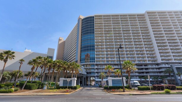 Ein mehrstöckiges Hotel mit modernem Design, das eine geschwungene Glasfassade und mehrere Balkone zeigt.