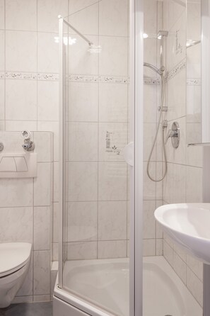 A modern bathroom with a glass-enclosed shower, a toilet, and a sink.
