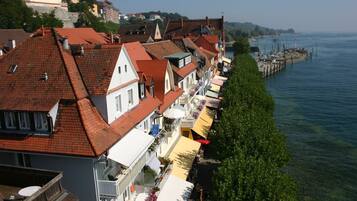 Gebäude mit roten Ziegeldächern säumen einen Uferweg, einige mit Balkonen und Außenbereich.