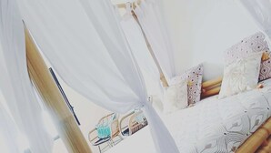 A bed with a canopy, pillows, and a bedside table with a lamp. - Villa Maho with breathtaking views (Petite Île)