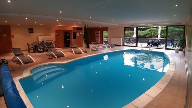 An indoor swimming pool with lounge chairs and a view of the outdoors. - 2-person apartment (Soultzmatt)