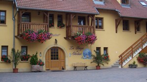 A traditional building with a wooden balcony, a wooden door, and a staircase leading to an upper floor. - 2-person apartment (Soultzmatt)