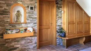 A room with a stone wall, wooden door, and a shelf with books and a statue. - 2-person apartment (Soultzmatt)