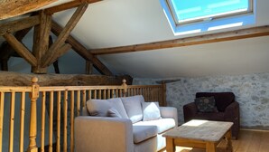A loft-style room with exposed wooden beams, a skylight, a sofa, a chair, and a wooden table. - Beautiful old cottage, with a  rear terrace giving stunning panoramic views.  (Lacépède)
